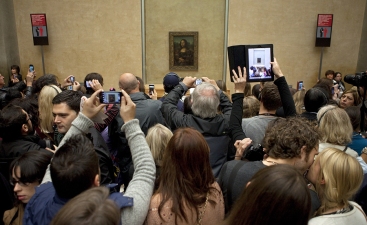 PARIS FRANCE - NOV 1ST 2013: Visitors at the Louvre Museum in Paris catch a glimpse of Leonardo Da Vinci's Mona Lisa on 1st November 2013.
